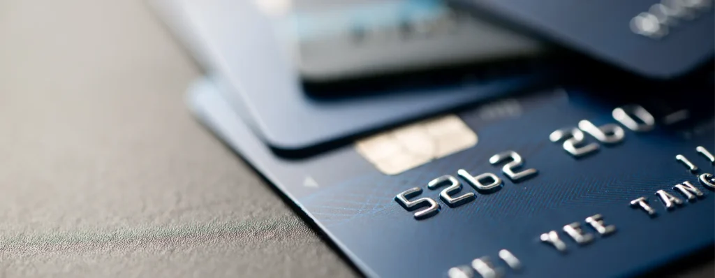 Close-up of blue business credit cards with silver embossed numbers and a chip on a dark grey background.